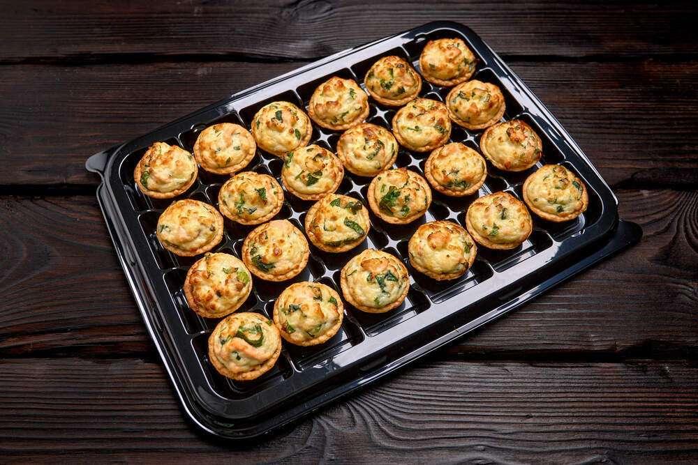 Bandeja de mini quiches variados de espinaca, jamón y cebolla para catering.